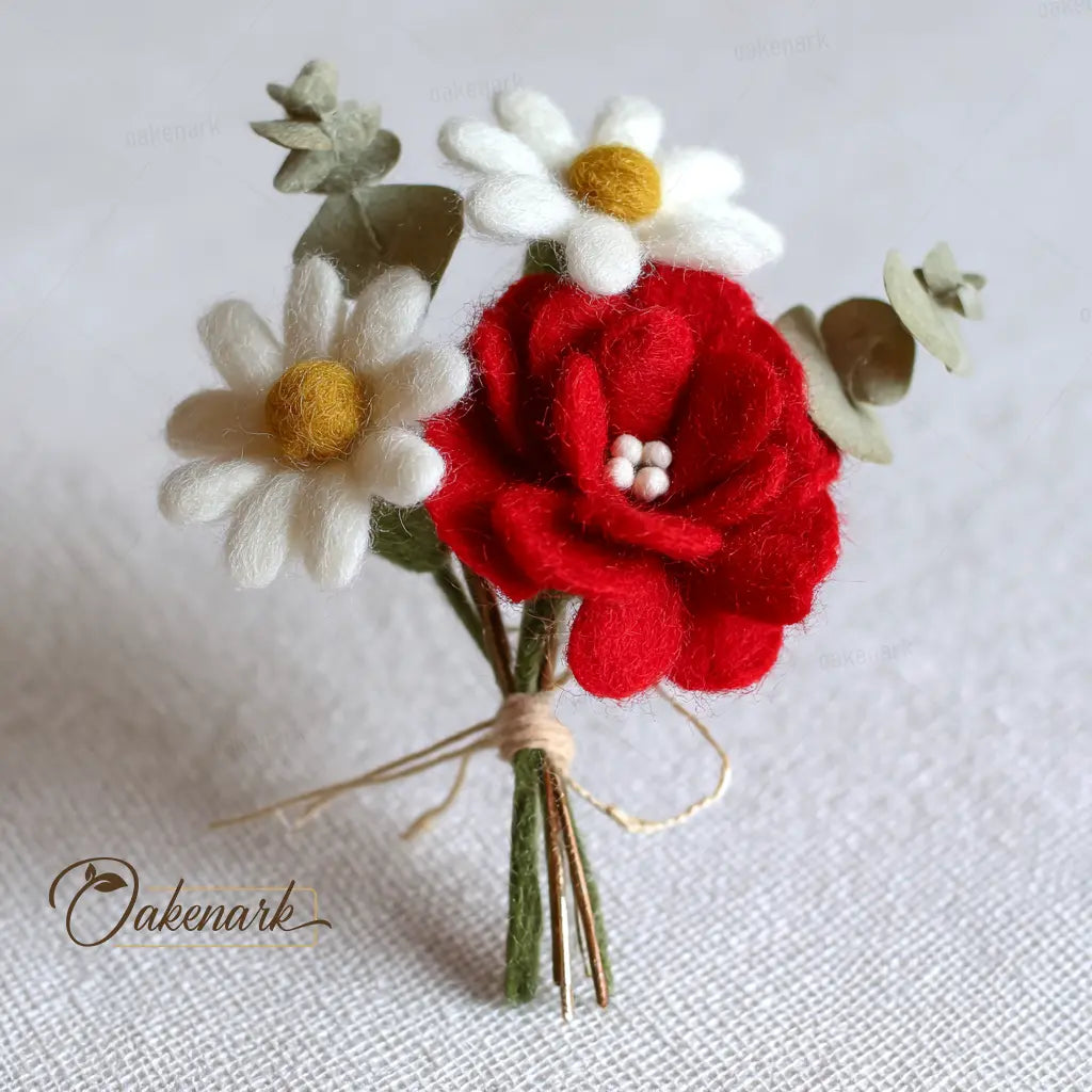 Bouquet of felt flowers including a red rose, white daisies, and green leaves on a light background.