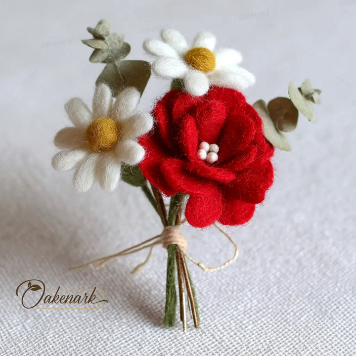 Bouquet of felt flowers including a red rose, white daisies, and green leaves on a light background.