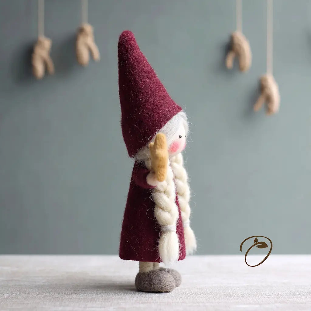 Side view of Nordic Mrs. Claus felt figurine showing her tall pointed hat, long white braid, and felt star.