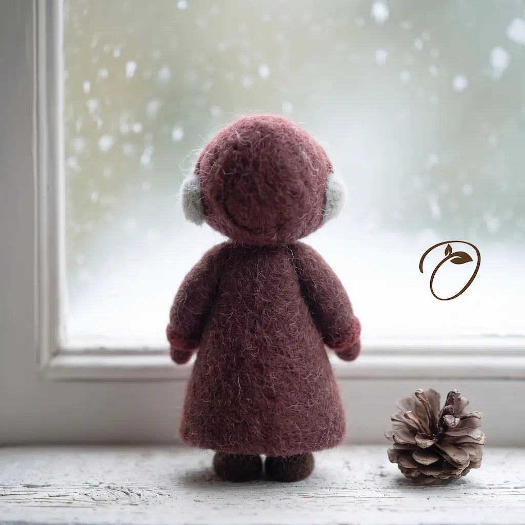 Side view of Mrs. Claus felt figurine showing her rounded burgundy bonnet, cream apron, red bag, and brown shoes.