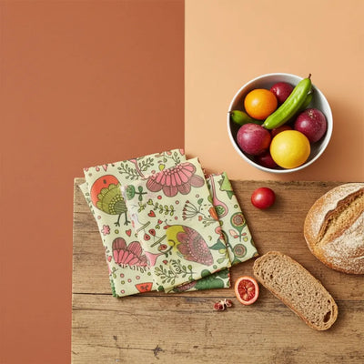 Round black bowl with cherry tomatoes and a floral-patterned lid on a white background