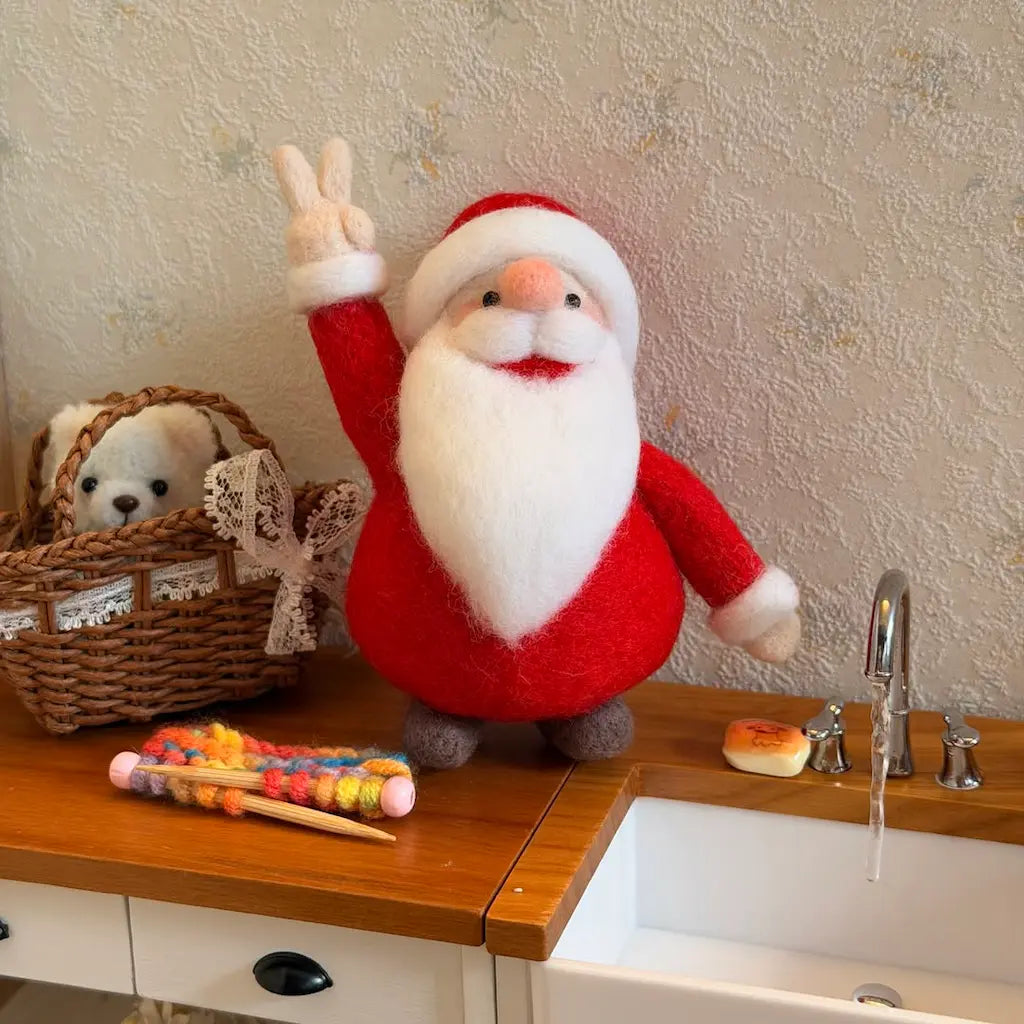 Felted Santa Claus figure on a kitchen counter with a basket and colorful items.