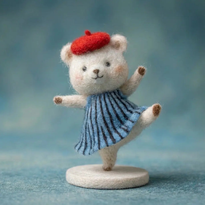 Teddy bear figurine wearing a red beret and blue dress on a textured surface with a blurred blue background
