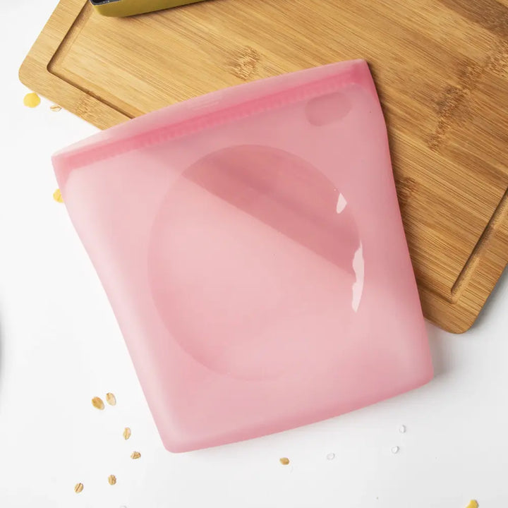 Pink silicone food storage bag on a wooden cutting board