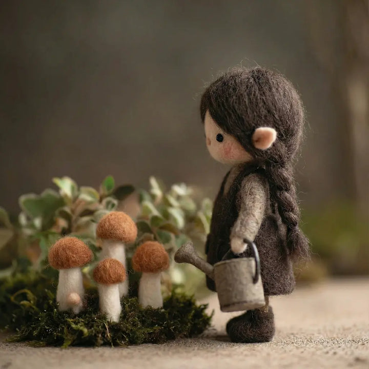 Small figurine of a person with a watering can standing next to mushrooms in a forest setting.