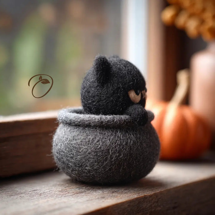 Side view of Grumpy Cauldron Cat felt figurine with black cat paws resting on cauldron rim