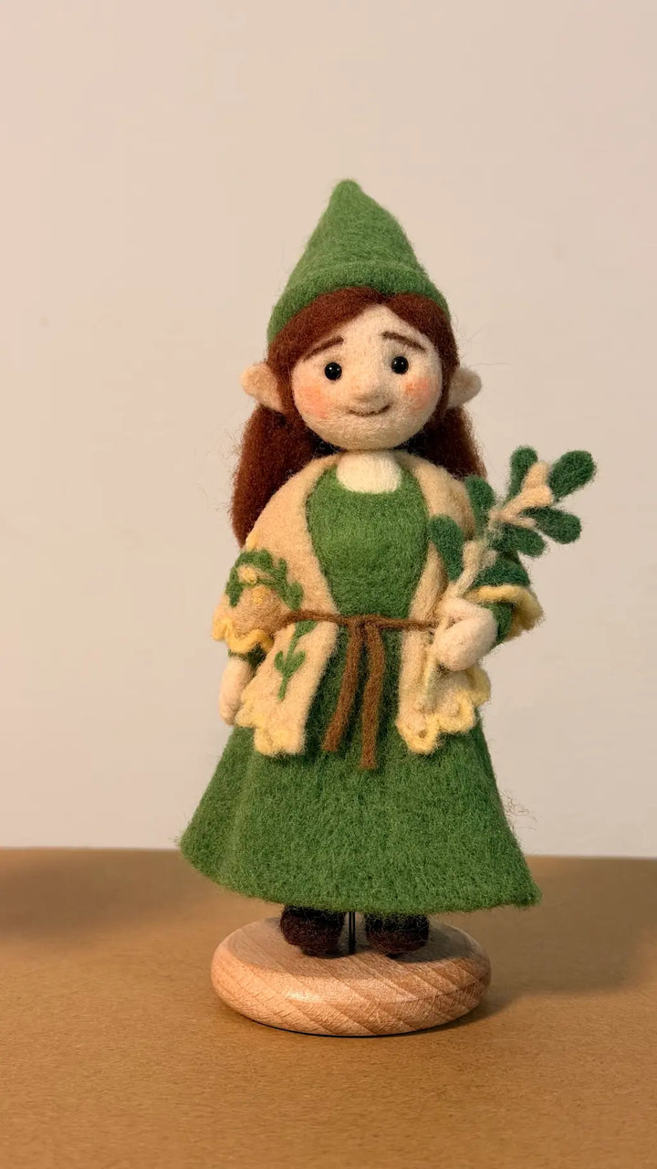 Felted figurine of a character in green attire with a plain background