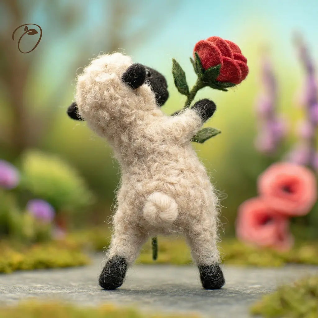 Toy sheep holding a red flower in a garden setting