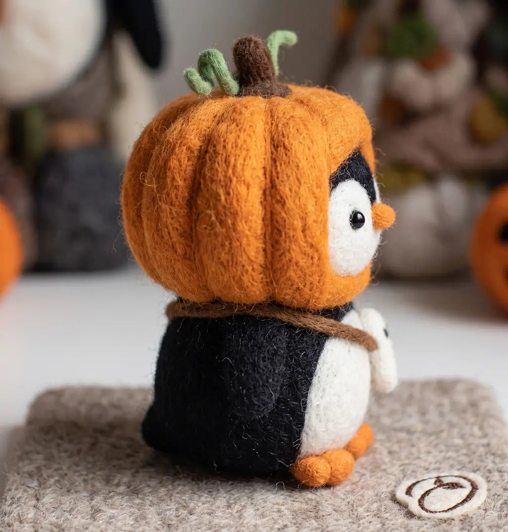Side view of Pumpkin Rascal Penguin felt figurine with segmented pumpkin hood and ghost charm