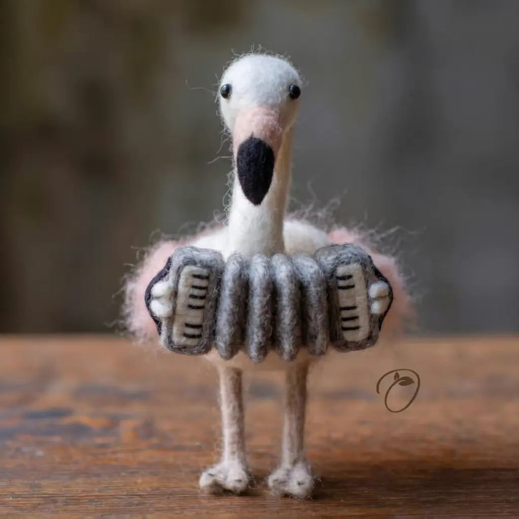 Felted toy bird with an accordion on a wooden surface