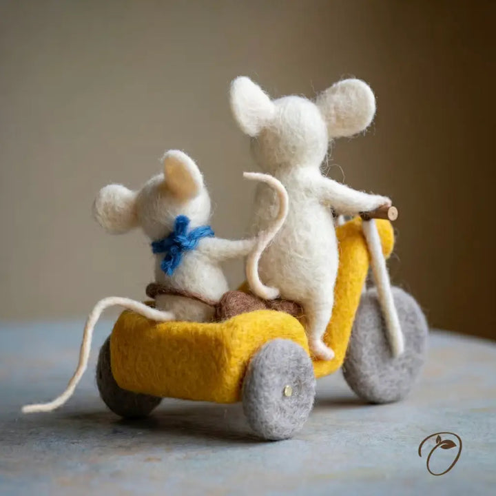 Two felted mouse figures on a yellow toy car with a plain background