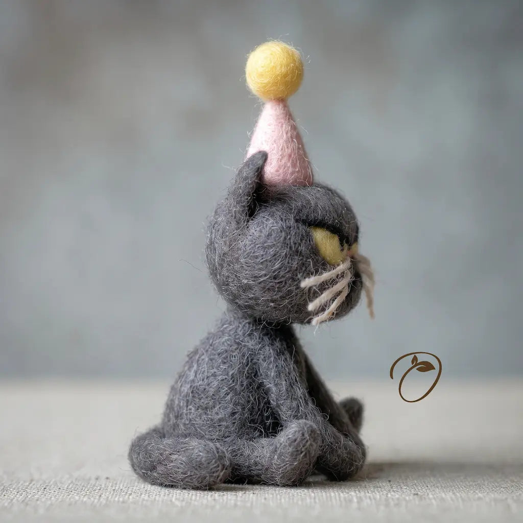 Handmade wool birthday cat figurine with yellow eyes and pink party hat, side view