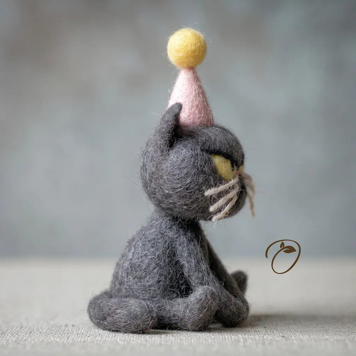 Handmade wool birthday cat figurine with yellow eyes and pink party hat, side view