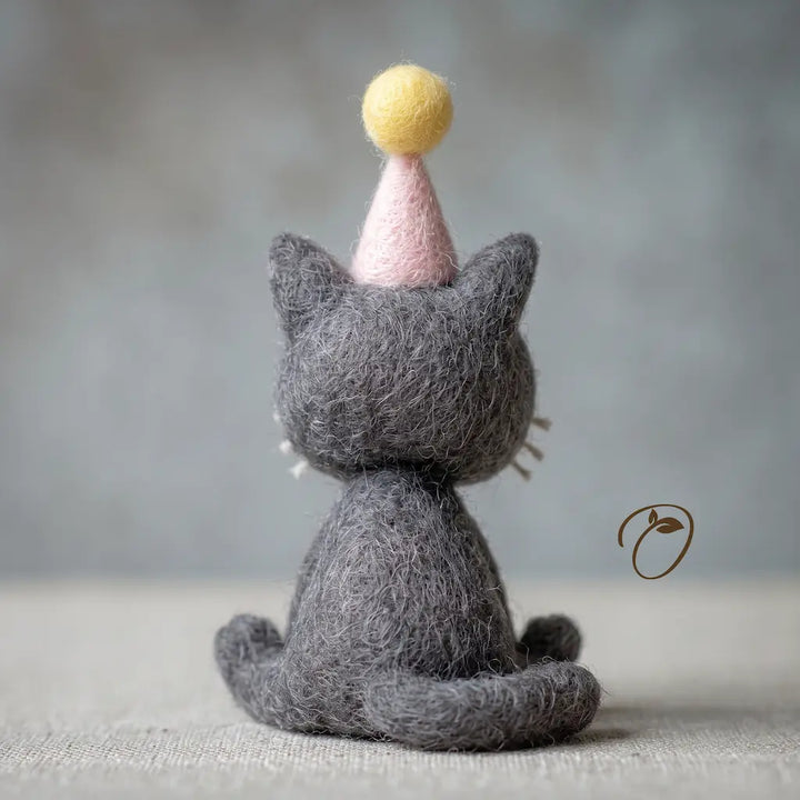 Dark gray needle-felted cat figurine with curved tail and pink party hat, back view
