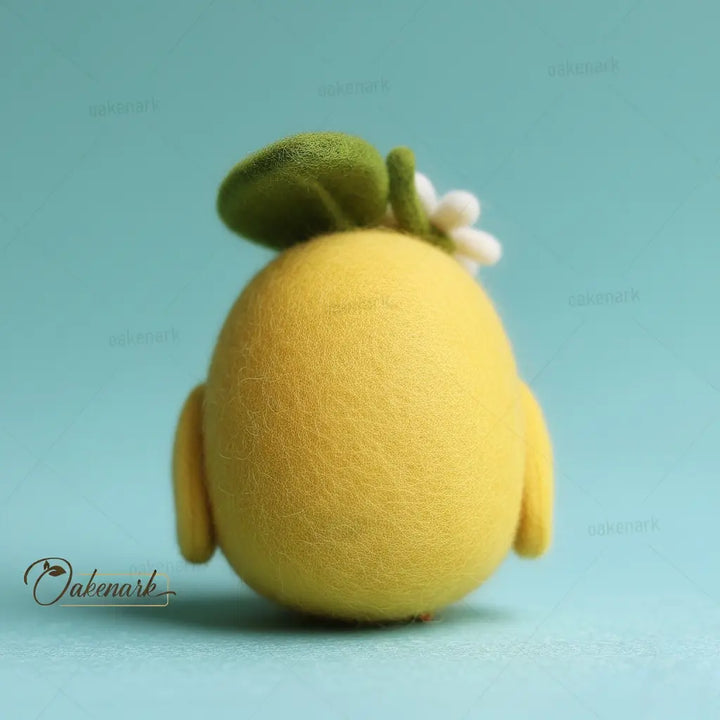 Yellow felt toy resembling a lemon with a green leaf on a light blue background