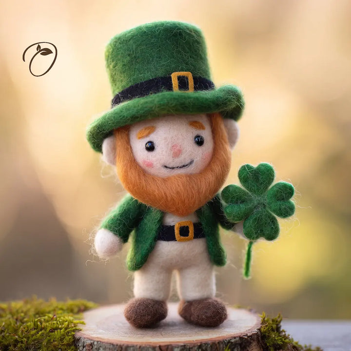 Smiling wool felt leprechaun in a green top hat, with an orange beard and a four-leaf clover held in one hand.