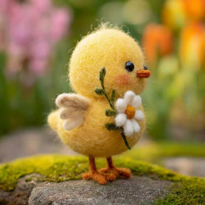 Yellow chick figurine holding a flower on a blurred natural background