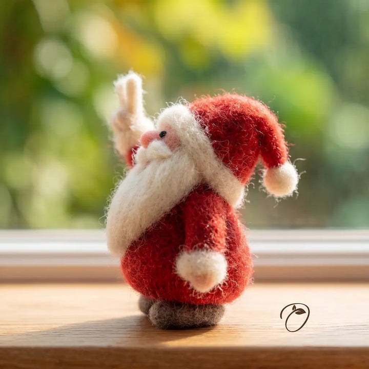 Felted Santa Claus figure on a wooden surface with a blurred green background