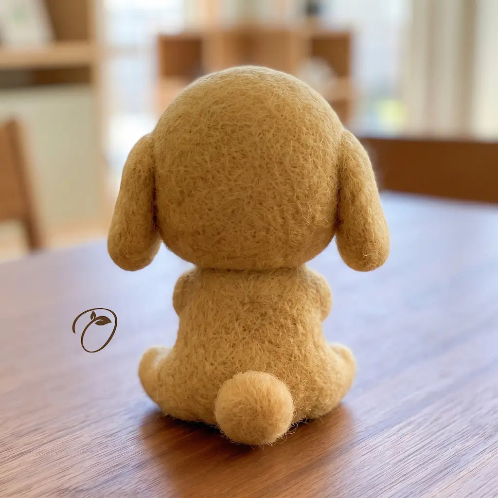 Back view of seated tan puppy wool felt figurine with floppy ears and rounded tail