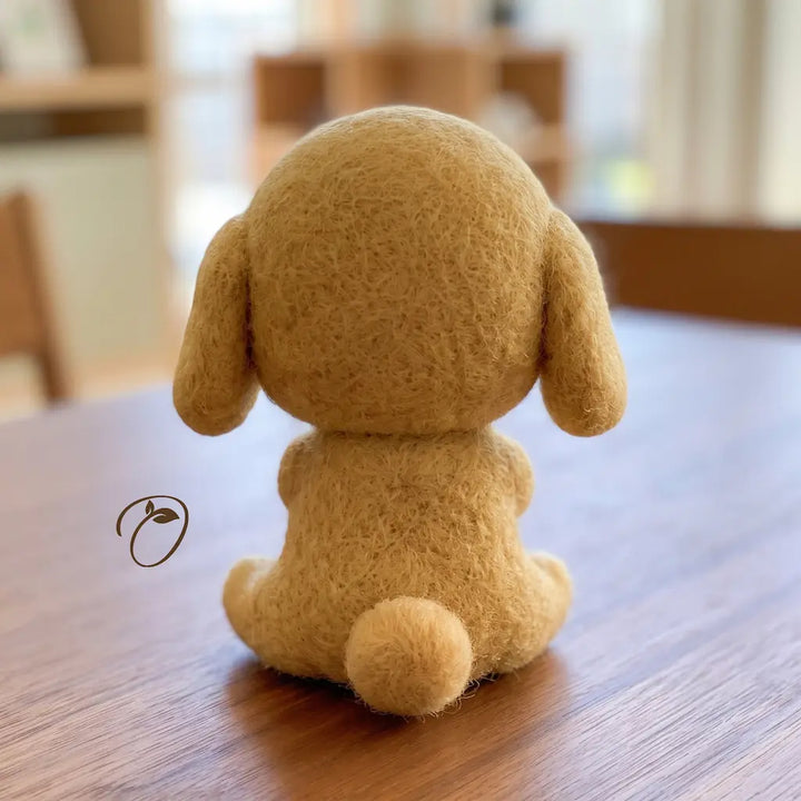 Back view of seated tan puppy wool felt figurine with floppy ears and rounded tail