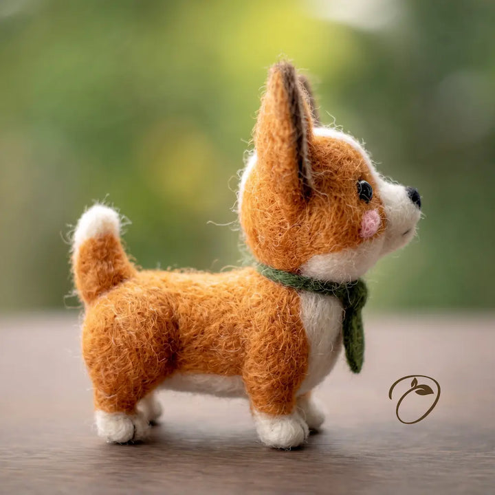Side view of standing corgi felt figurine with moss-green scarf