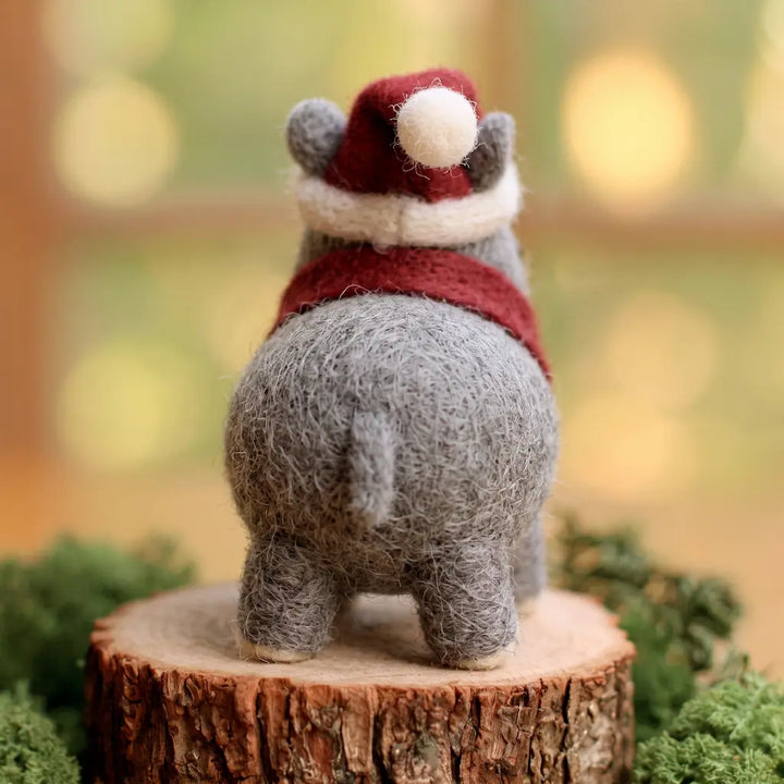 Back view of a gray felt Christmas rhino showing its short tail, red scarf and Santa hat with a white pom-pom.