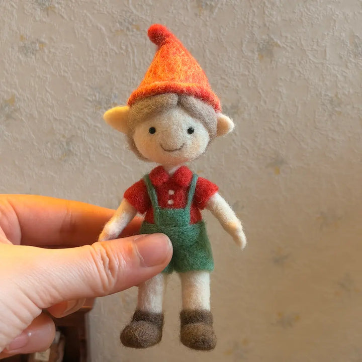 Small toy figure with a red hat and green overalls held by a hand against a neutral background