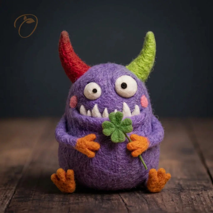 Purple Clover Monster wool felt figurine holding a four-leaf clover with mismatched horns, pointed teeth and orange hands