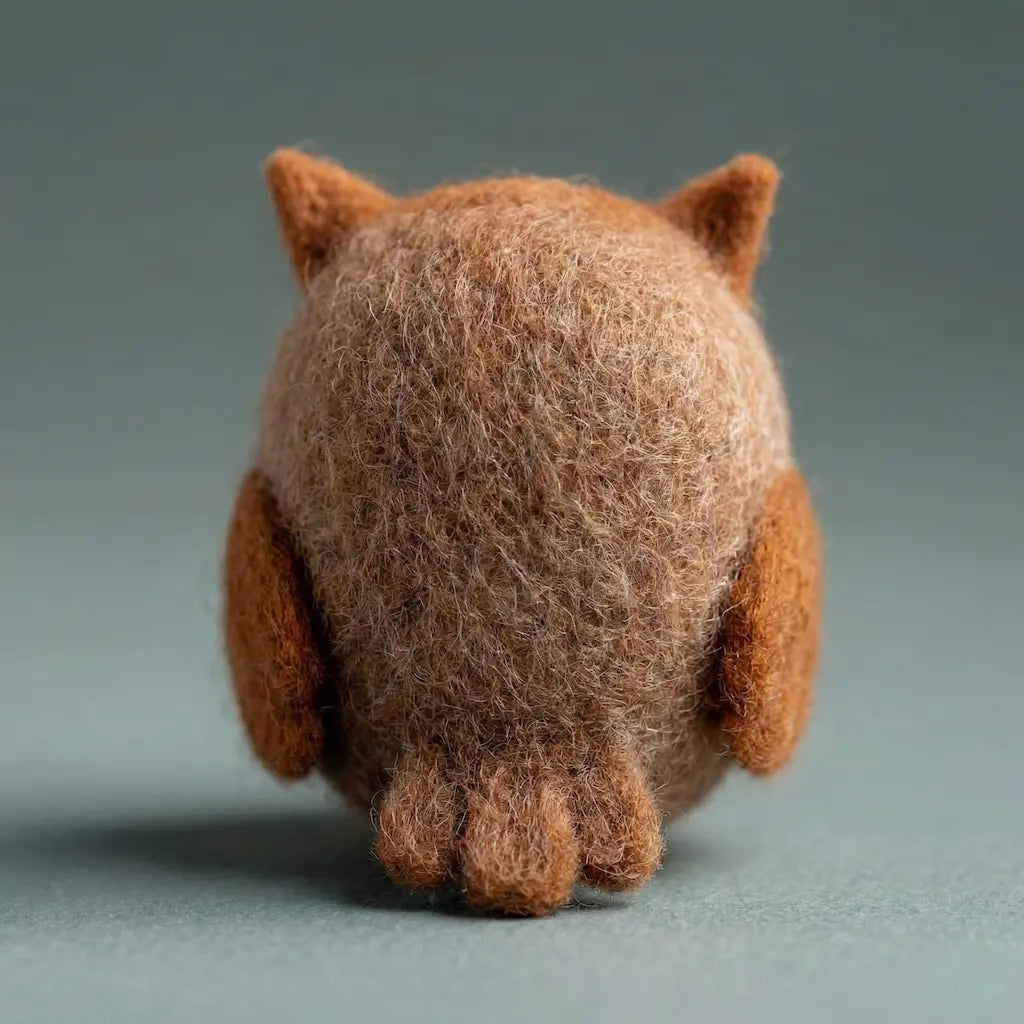 Brown plush toy resembling a cat from behind on a gray background