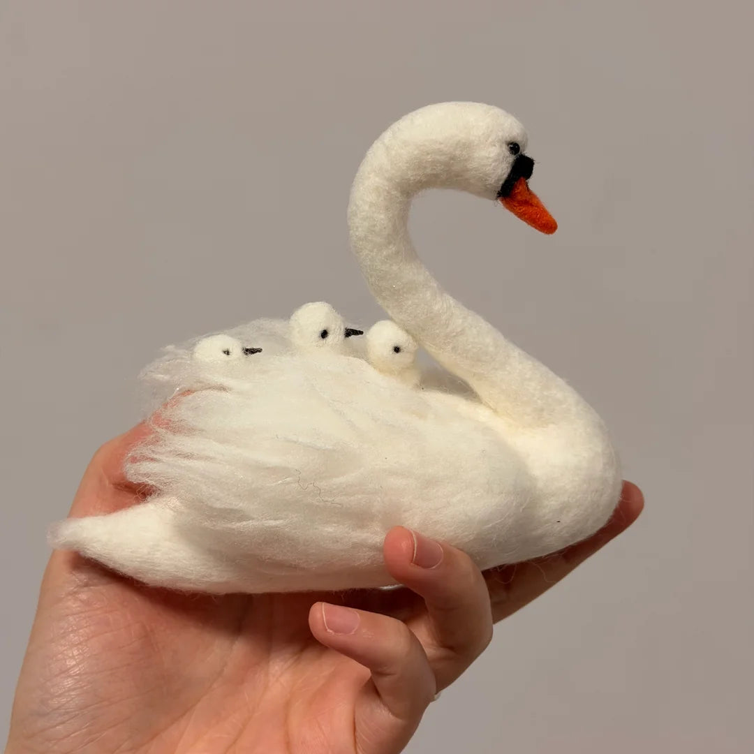 White swan plush toy with three smaller swan toys on a plain background