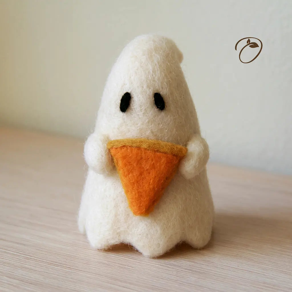 Front view of an ivory wool felt ghost holding an orange pumpkin pie slice with golden crust, with dark oval eyes and a scalloped hem.