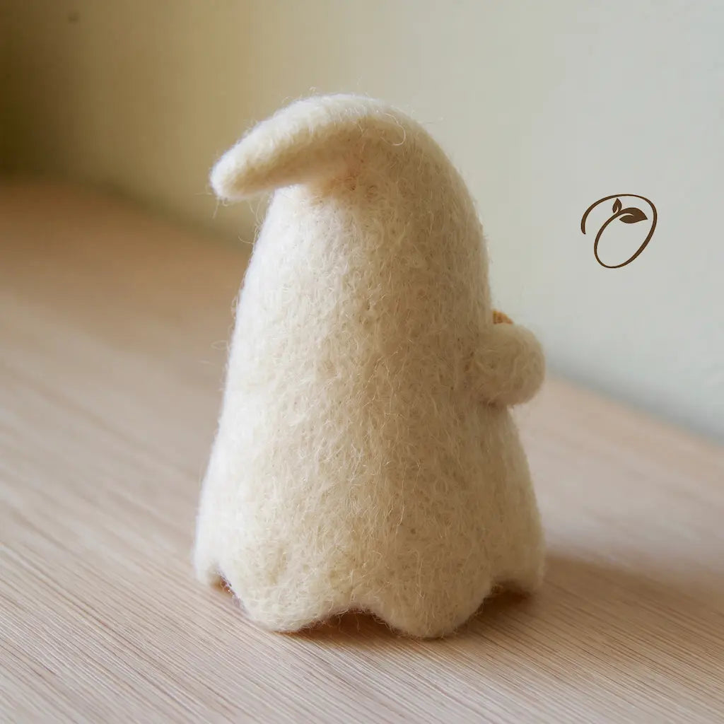 Rear view of an ivory wool felt ghost showing its curved head tip, rounded back, scalloped hem, and a small arm at the side.