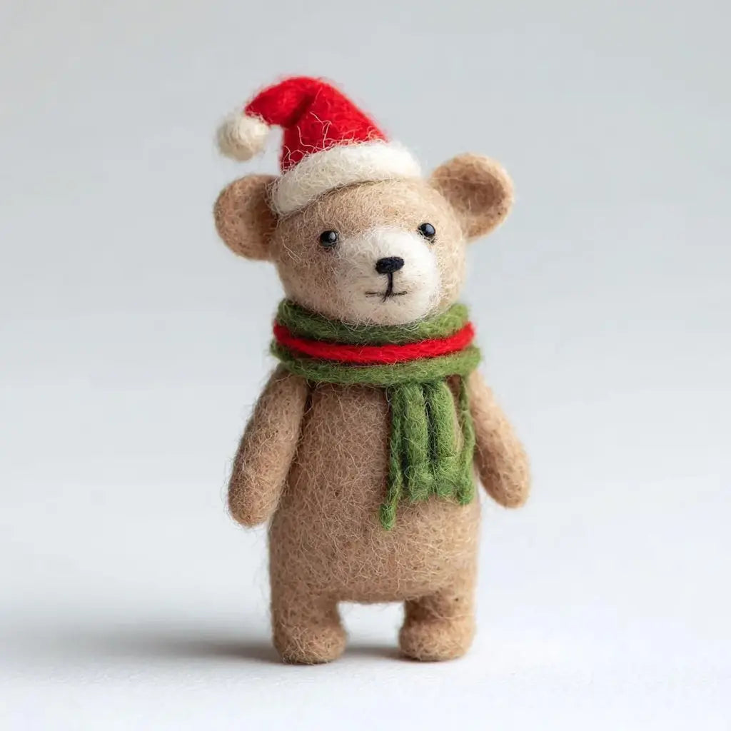 Teddy bear wearing a Santa hat and green scarf on a light gray background