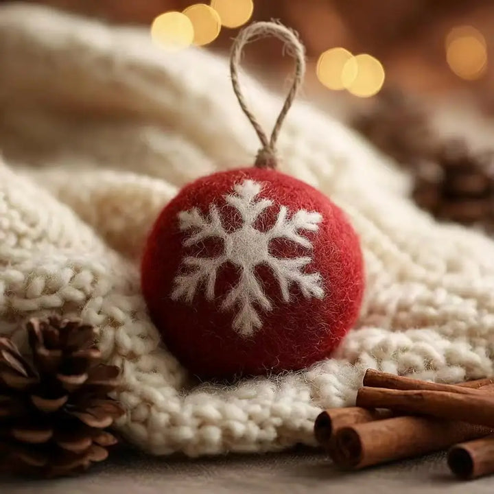 Red ornament with a white snowflake design on a textured surface with blurred lights in the background