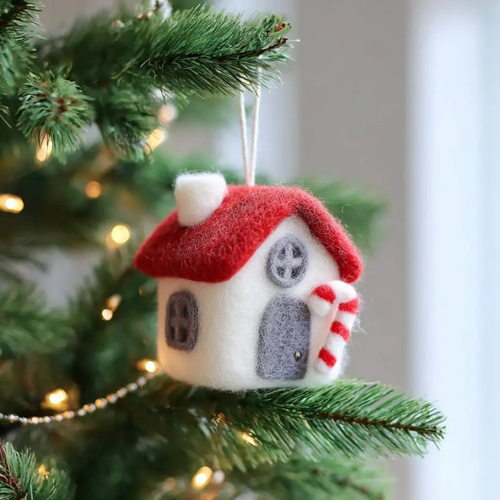 Decorative house ornament on a Christmas tree with lights.