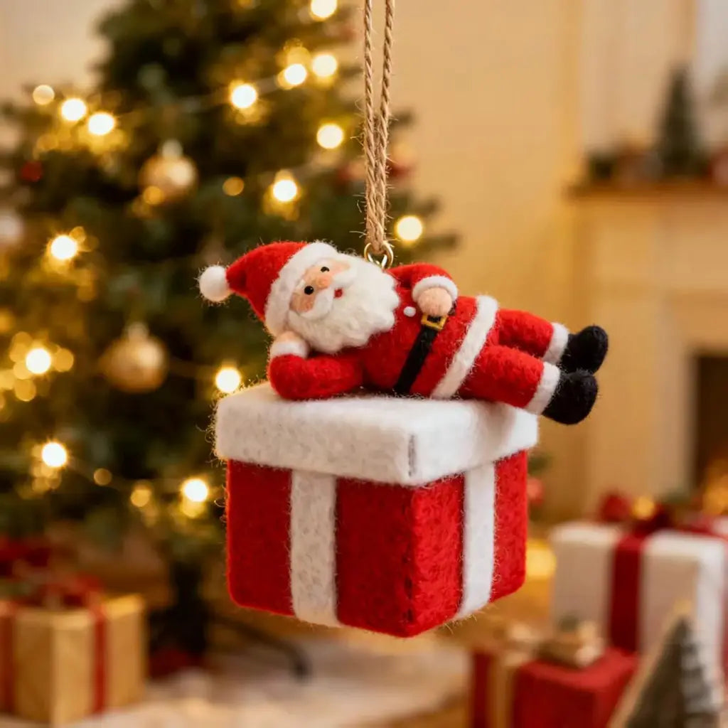 Decorative ornament of Santa Claus on a gift box with a Christmas tree in the background