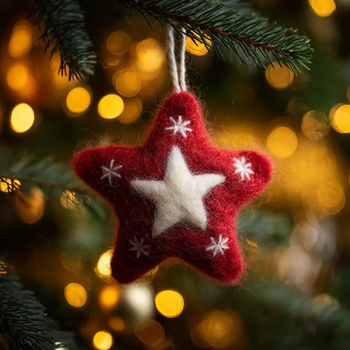 Red and white star-shaped Christmas ornament on a tree branch with blurred lights in the background