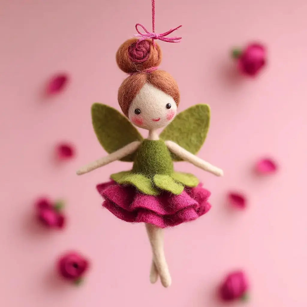 Felt fairy doll with green and pink dress hanging against a pink background with small flowers.