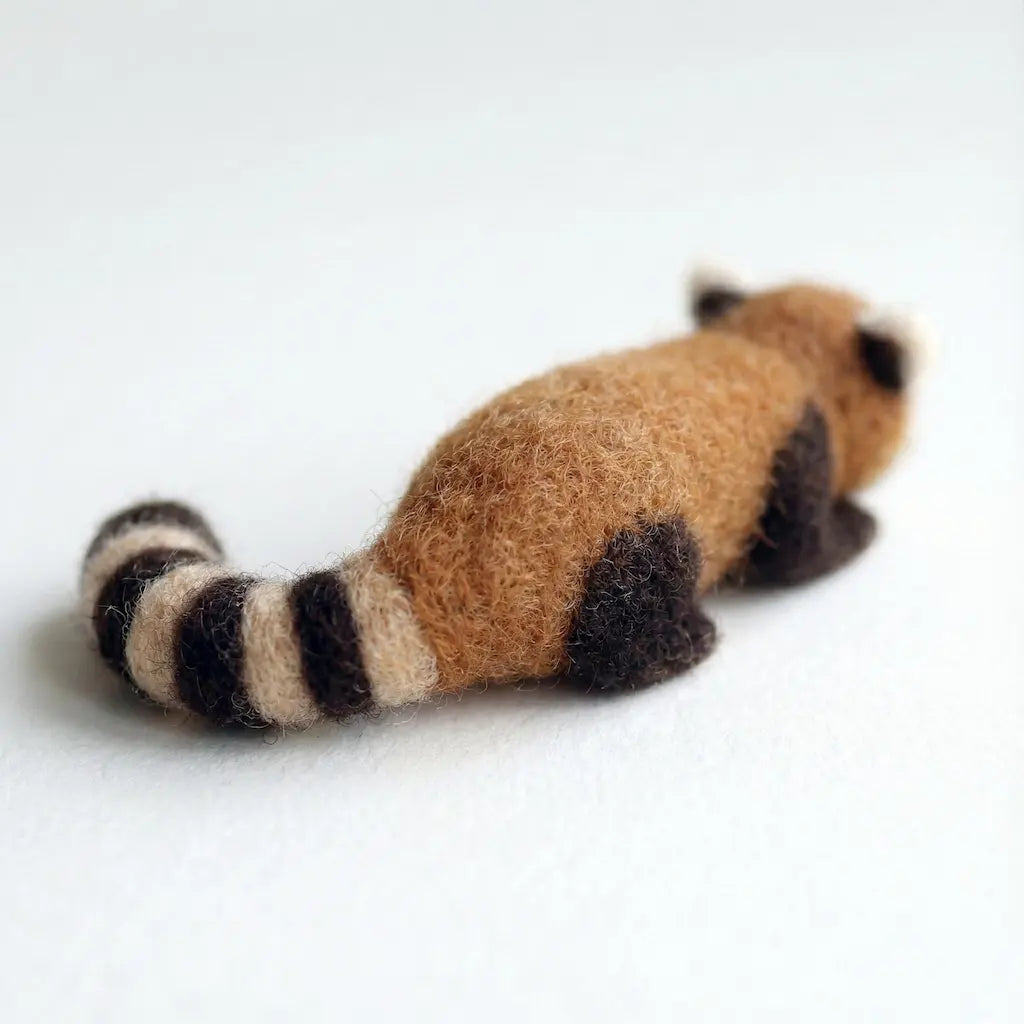 Felted raccoon toy on a white background