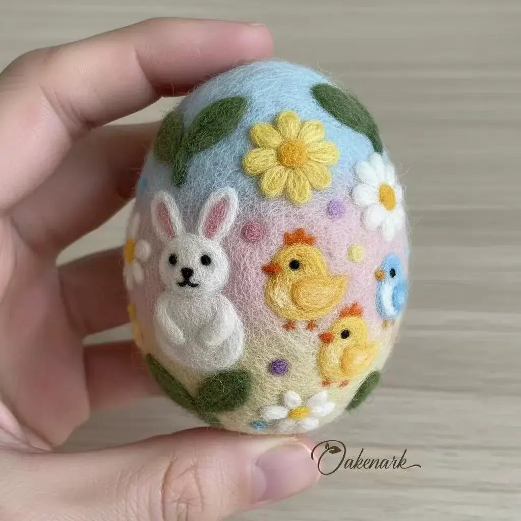 Decorative Easter egg with embroidered bunny, chick, and flowers held by a hand.