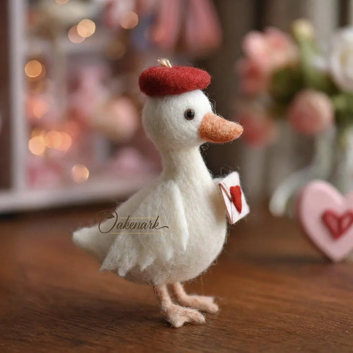 White felted duck figurine with a red hat on a wooden surface, blurred background with flowers and lights.