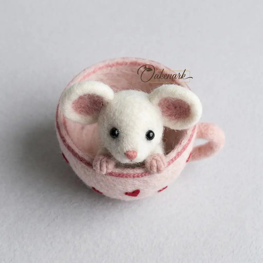 Felted mouse toy inside a pink cup with red hearts on a light gray background