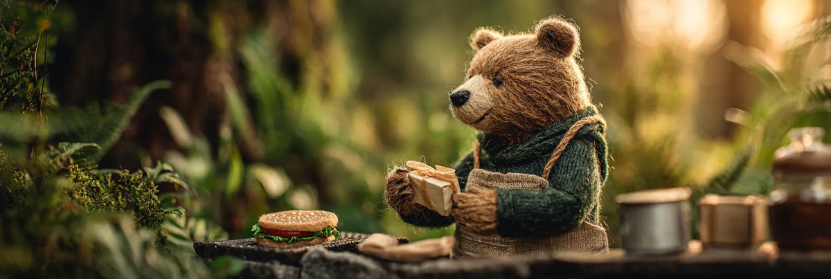Handmade wool felt father bear holding a Father's Day gift beside a backyard barbecue