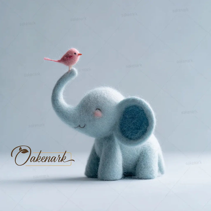 Felted toy elephant with a pink bird on its trunk against a light gray background, featuring the brand &