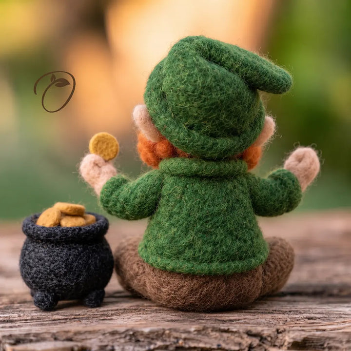 Back view of a seated felt leprechaun showing a folded green cap, green coat, raised arms and a pot of felt coins.