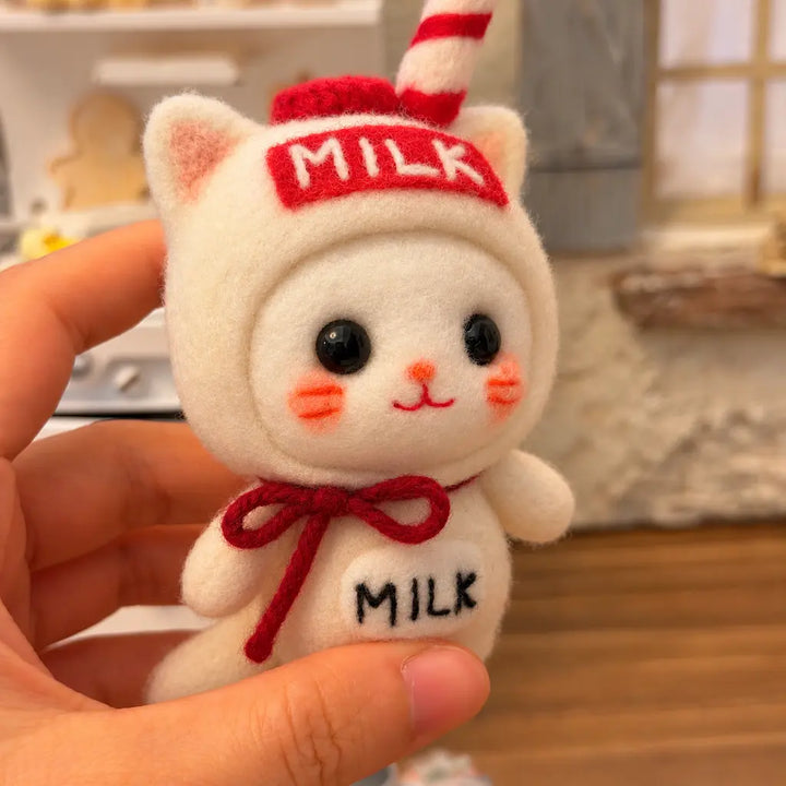Close-up of the Milk Carton Cat felt figurine with glossy black eyes, rosy cheeks, a red bow and MILK lettering.