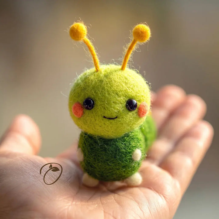 A small felt caterpillar figurine with yellow antennae, black eyes, and pink cheeks resting on a person&