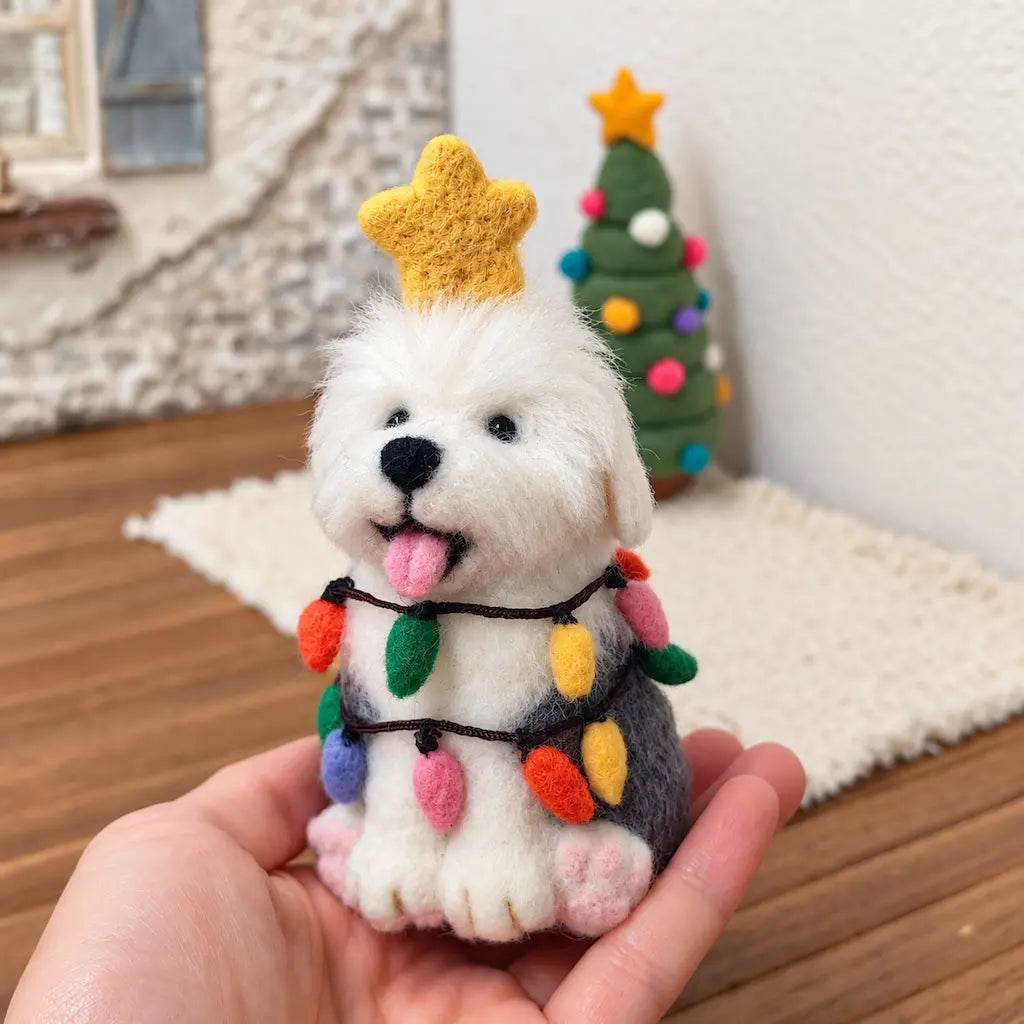 A hand holding a wool felt sheepdog with a yellow star and colorful felt lights.