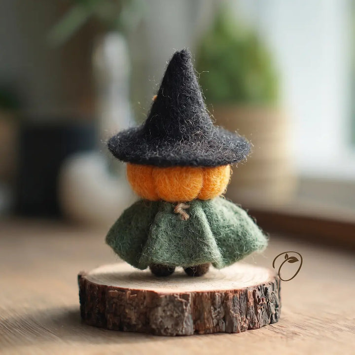 Back view of handmade pumpkin witch with sage-green wool cape