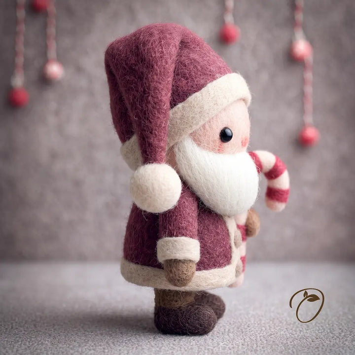 A handcrafted felt Santa Claus figurine in burgundy and cream, holding a red and white striped candy cane, set against a soft gray background with hanging decorative ornaments.